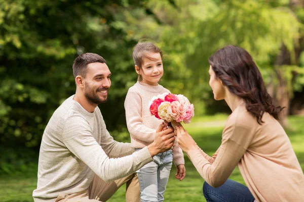 Szczęśliwa rodzina z kwiatami w lato park — Zdjęcie stockowe