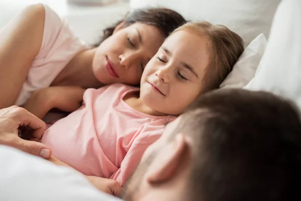 Família feliz dormindo na cama em casa — Fotografia de Stock