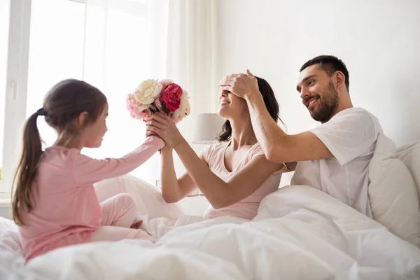 Gelukkig meisje geven van bloemen te moeder in bed thuis — Stockfoto