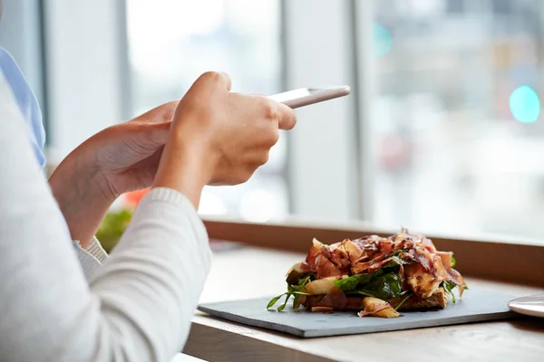 Женщина со смартфоном и салатом из ветчины в ресторане — стоковое фото
