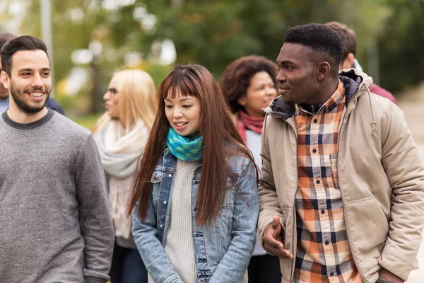 Gelukkige vrienden wandelen langs het herfstpark — Stockfoto