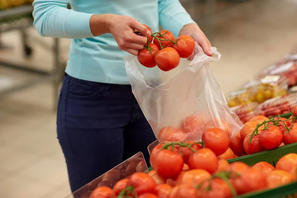 Vrouw met tas kopen van tomaten in supermarkt — Stockfoto