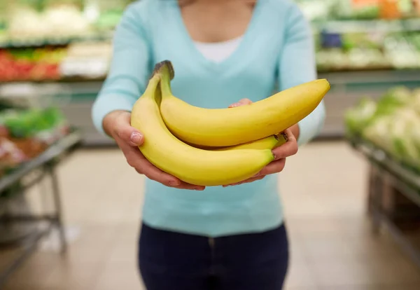 Vrouw met bananen in supermarkt — Stockfoto
