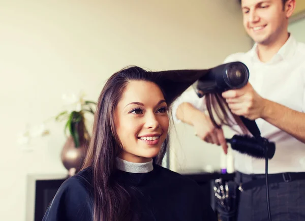 Szczęśliwa kobieta ze stylistką robi fryzurę w salonie — Zdjęcie stockowe