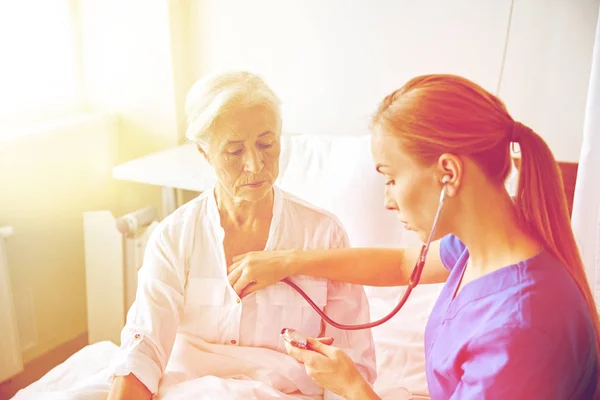 Enfermera con estetoscopio y mujer mayor en la clínica — Foto de Stock