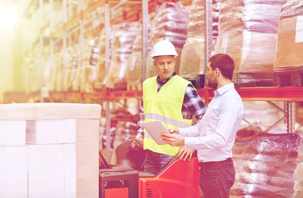 Mannen met tablet pc en vorkheftruck magazijn — Stockfoto