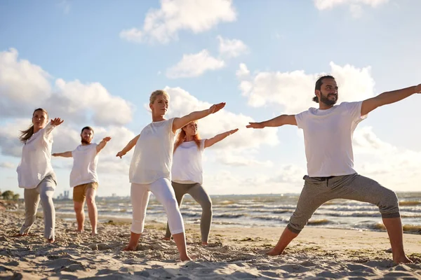 Gruppe von Leuten, die Yoga-Übungen am Strand machen — Stockfoto