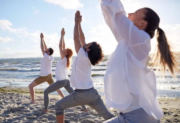 Grupa osób zarabiających ćwiczenia jogi na plaży — Zdjęcie stockowe