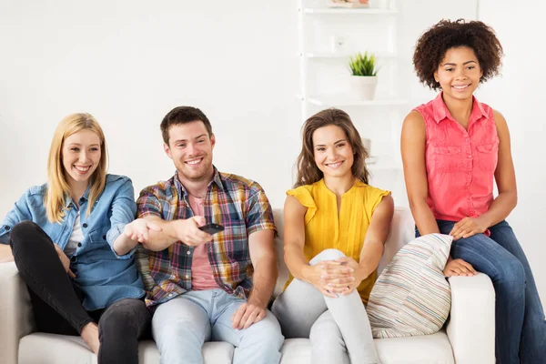 Amici felici con telecomando guardando la tv a casa — Foto Stock