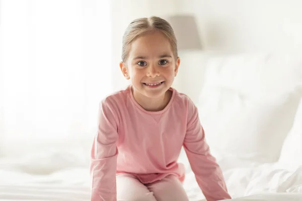 Heureuse petite fille sur le lit à la maison chambre — Photo