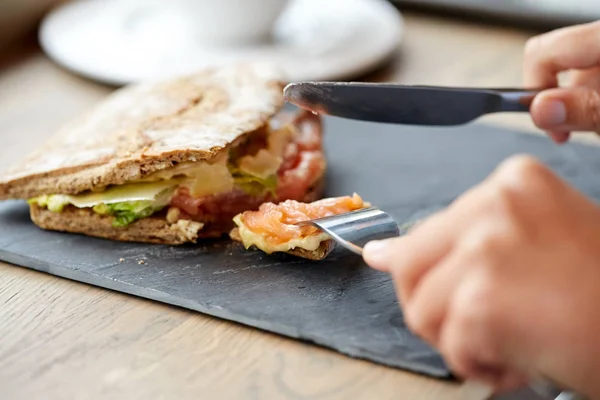 Persona comiendo sándwich de salmón panini en el restaurante —  Fotos de Stock