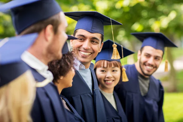 Happy students or bachelors in mortar boards — Stock Photo, Image