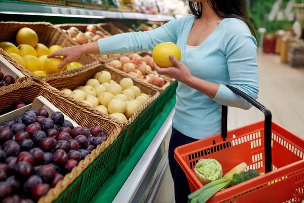 Mujer con cesta comprando pomelo en la tienda de comestibles — Foto de Stock