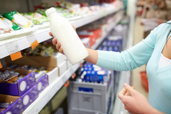 Vrouw met melk fles bij de kruidenier of supermarkt — Stockfoto