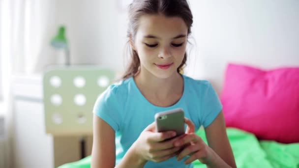 Улыбающаяся девушка пишет смс на смартфоне дома — стоковое видео