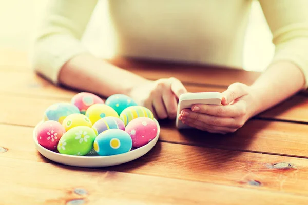 Close up of hands with easter eggs and smartphone — Stock Photo, Image