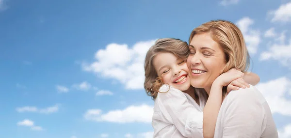 Happy mother and daughter hugging over blue sky — Stock Photo, Image