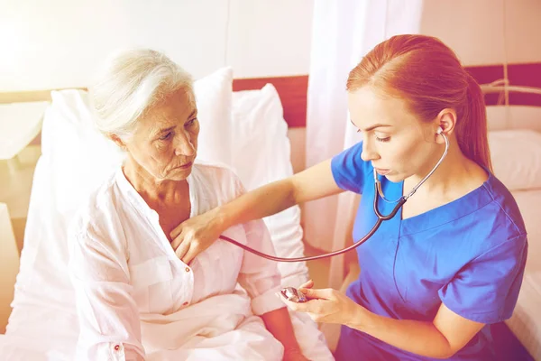 Sjuksköterska med stetoskop och senior kvinna vid kliniken — Stockfoto