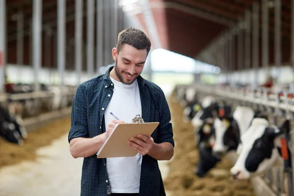 Landwirt mit Klemmbrett und Kühen im Kuhstall auf Bauernhof — Stockfoto