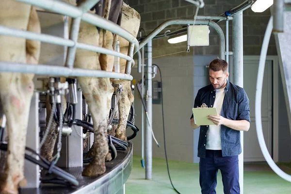 Férfi vágódeszkával és tejelő tehenekkel a tejgazdaságban — Stock Fotó