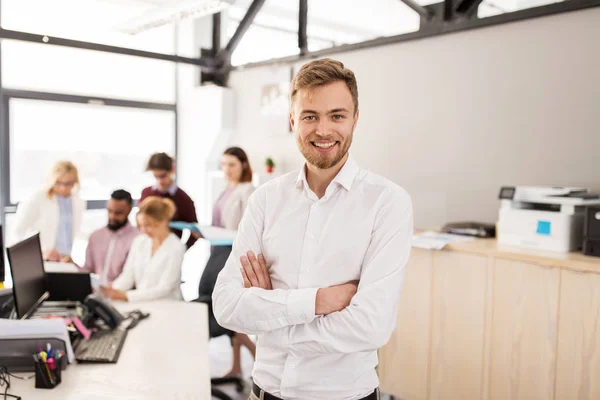 Happy young man over creative team in office — Stock Photo, Image