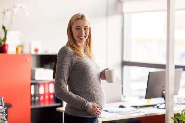 Empresaria embarazada con taza de té en la oficina — Foto de Stock
