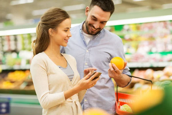 Para z smartphone zakupie pomarańcze w grocery — Zdjęcie stockowe