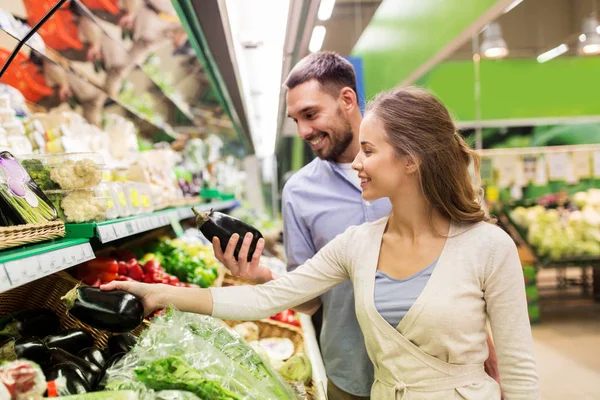 Happy couple buying eggplant at grocery store — Stock Photo, Image