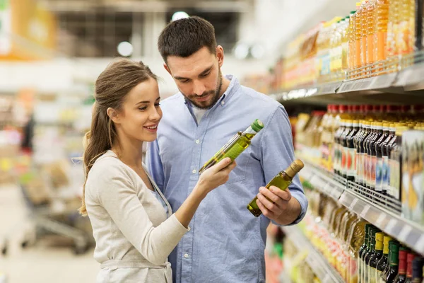 Счастливая пара покупает оливковое масло в продуктовом магазине — стоковое фото