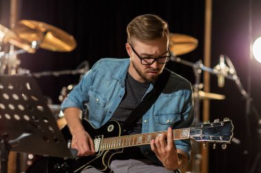 man playing guitar at studio rehearsal clipart