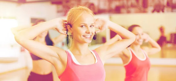 Grupo de personas sonrientes haciendo ejercicio en el gimnasio — Foto de Stock