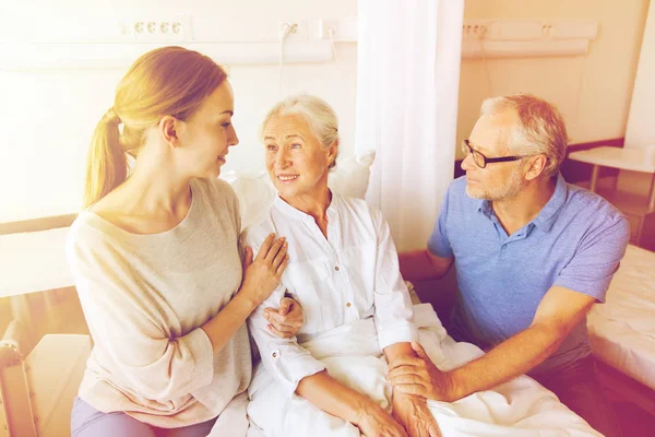 Счастливая семья, посещающая пожилую женщину в больнице — стоковое фото