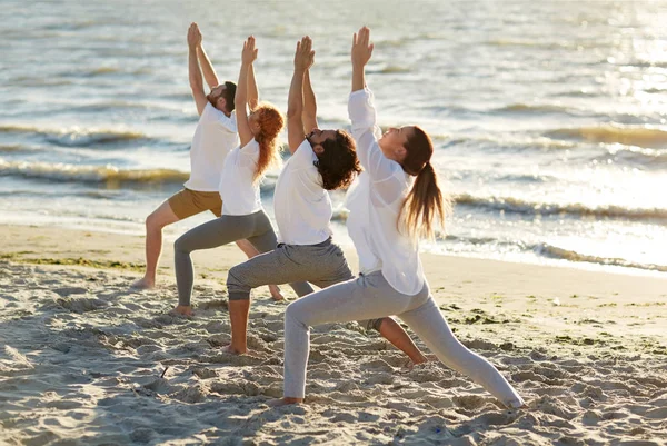 Groep mensen die yoga oefeningen op strand — Stockfoto