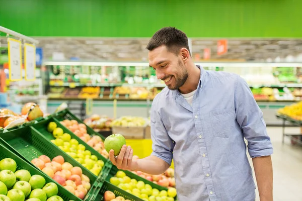 Homem feliz comprando maçãs verdes no supermercado — Fotografia de Stock