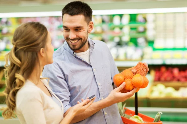 Feliz pareja comprar naranjas en la tienda de comestibles —  Fotos de Stock