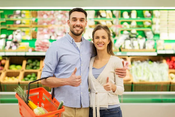 Lyckliga par med matkorg vid livsmedelsbutik — Stockfoto