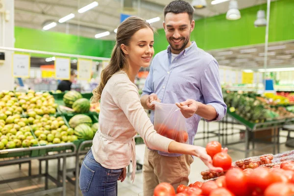 Счастливая пара покупает помидоры в продуктовом магазине — стоковое фото