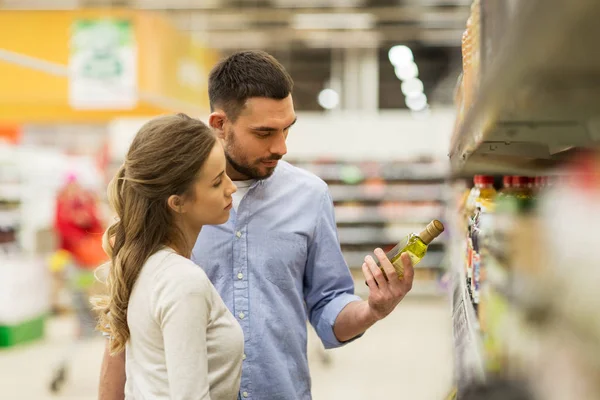 Щаслива пара купує оливкову олію в продуктовому магазині — стокове фото