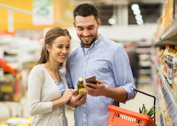 Paar mit Smartphone kauft Olivenöl im Supermarkt — Stockfoto