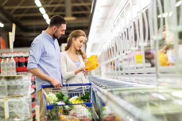 Pareja con carrito de la compra de alimentos en la tienda de comestibles — Foto de Stock