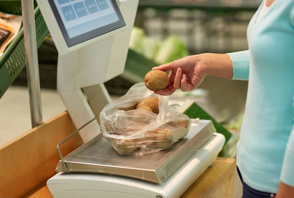 Žena o hmotnosti brambor v měřítku v obchodu s potravinami — Stock fotografie
