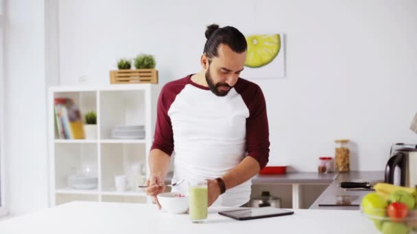 Homem com tablet pc comendo café da manhã em casa — Vídeo de Stock