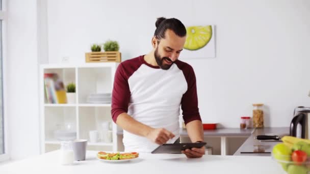 Man with tablet pc eating breakfast at home — Stock Video