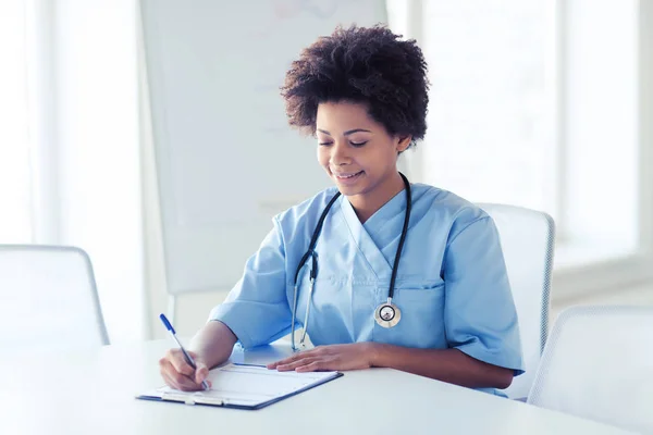 Счастливая женщина врач или медсестра, пишущая в буфер обмена — стоковое фото