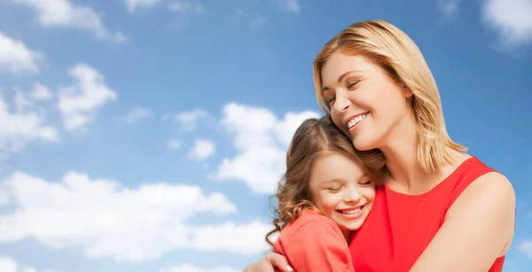 Feliz madre e hija abrazándose sobre el cielo azul —  Fotos de Stock