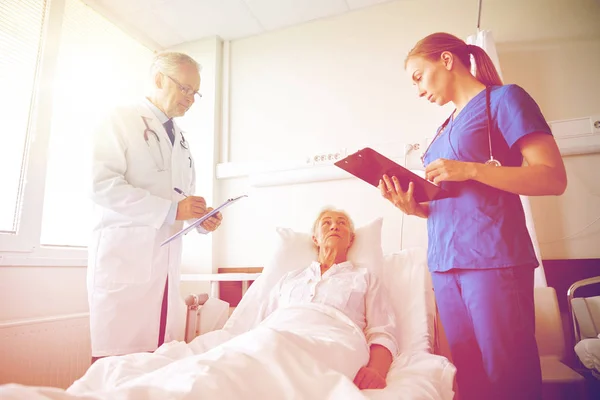 Läkare och sjuksköterska besöker äldre kvinna på sjukhuset — Stockfoto
