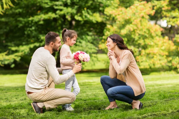 Gelukkige familie met bloemen in de zomer park — Stockfoto