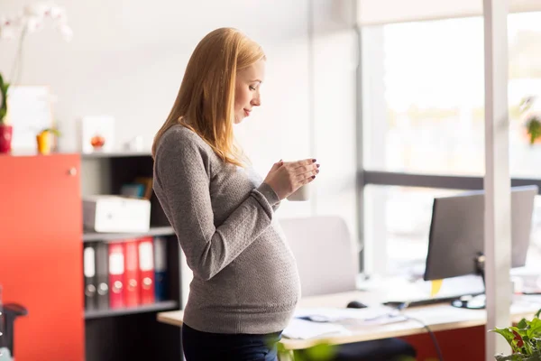 Empresaria embarazada con taza de té en la oficina — Foto de Stock