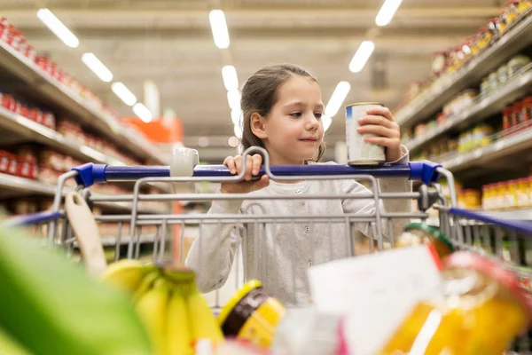 Menina com comida no carrinho de compras na mercearia — Fotografia de Stock