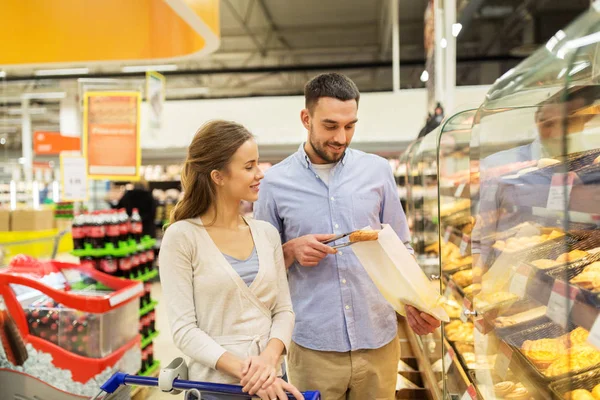 Glückliches Paar mit Einkaufswagen im Lebensmittelgeschäft — Stockfoto